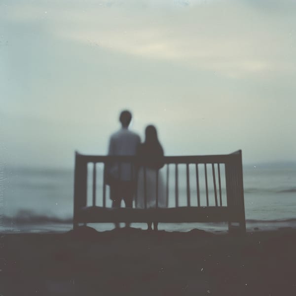  A man and woman on a beach standing with their back to an empty crib